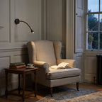 Astro Fosso Switched Reading Light in Bronze lit beside an armchair in a panelled Georgian sitting room