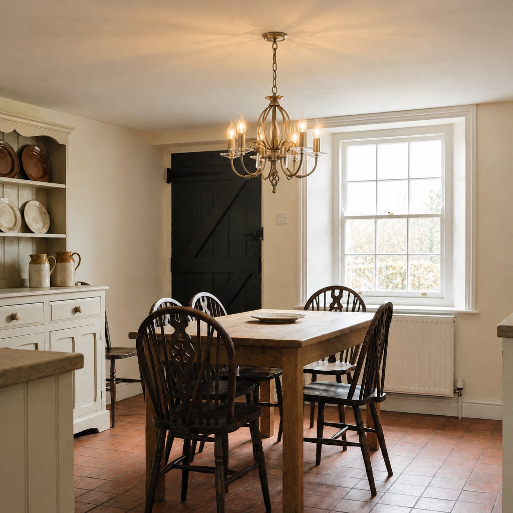 Elstead Aegean 5 Light Chandelier in Aged Brass lit over an oak table in a Victorian farmhouse kitchen-diner
