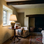 Elstead Arum Lily Table Lamp in Green with Cream Shade lit in a beamed country cottage sitting room