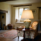 Elstead Arum Lily Table Lamp in Green with Cream Shade lit in a beamed country cottage sitting room