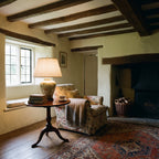 Elstead Arum Lily Table Lamp in Green with Cream Shade lit in a beamed country cottage sitting room