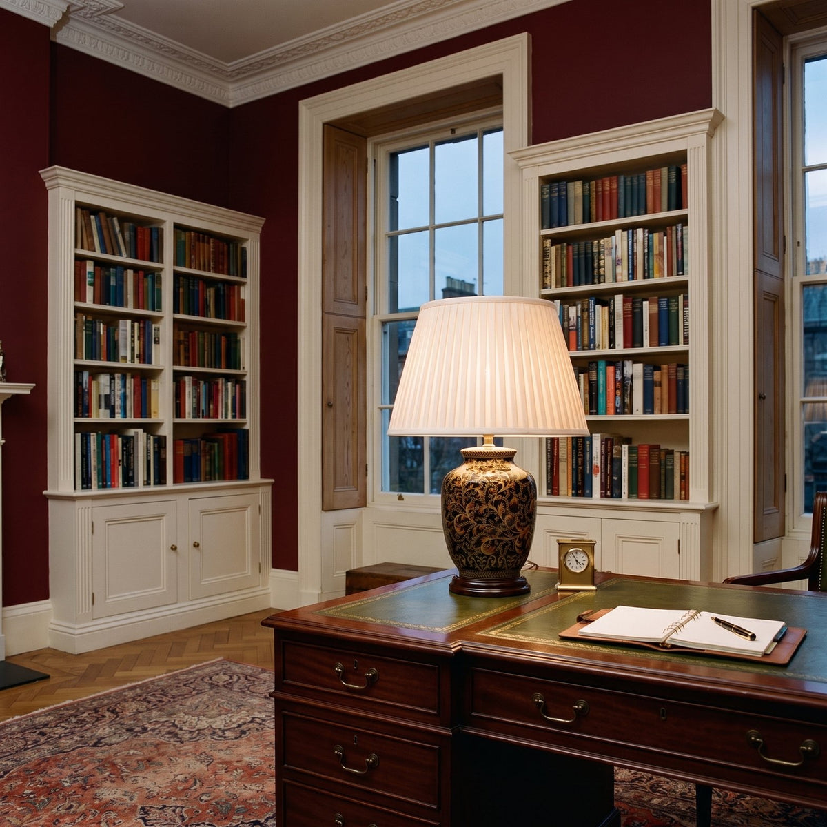 Elstead Morris Small Table Lamp in Black Gold lit on a desk in an oxblood red Georgian study
