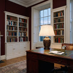 Elstead Morris Small Table Lamp in Black Gold lit on a desk in an oxblood red Georgian study