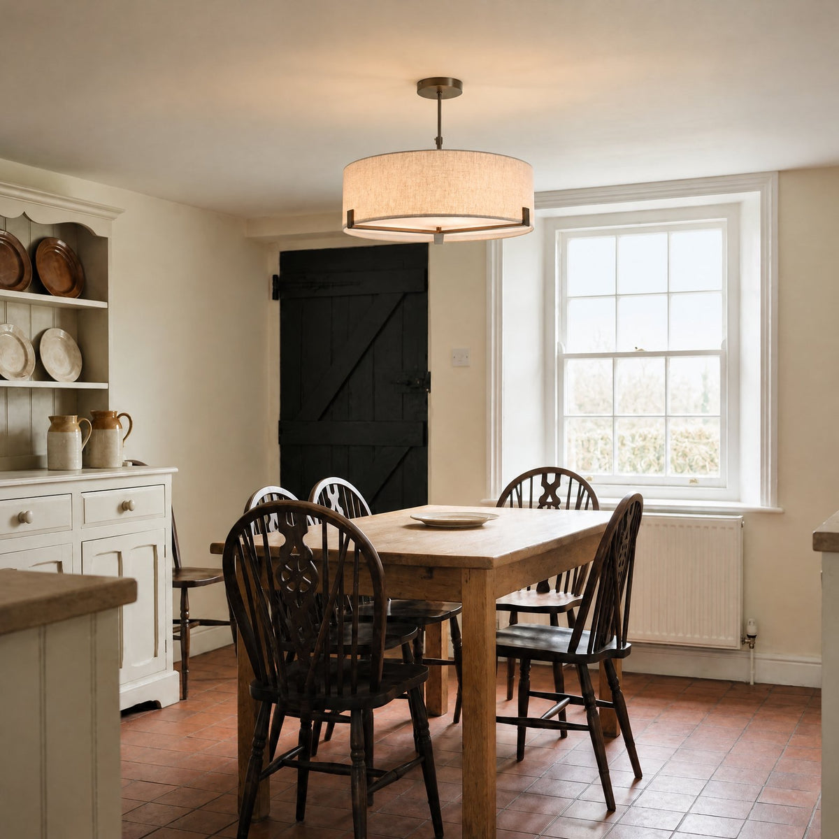 Endon Hayfield 3 Light Pendant in Brushed Bronze with Natural Linen lit over an oak table in a Victorian farmhouse kitchen-diner