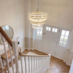 Marietta 16 light tiered pendant in antique brass in a double height entrance hall, seen from the landing