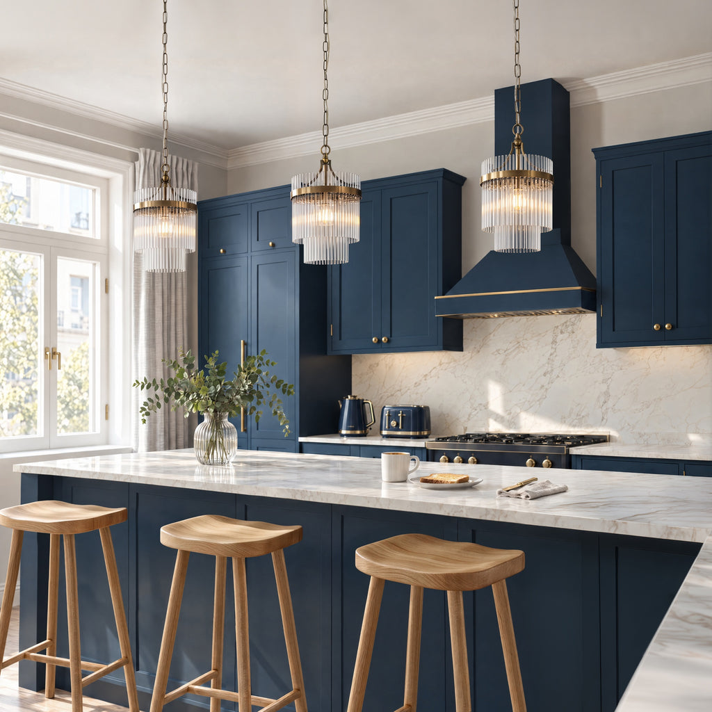 Three Marietta single pendants in antique brass hung in a row over a marble kitchen island with navy shaker cabinets