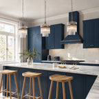 Three Marietta single pendants in antique brass hung in a row over a marble kitchen island with navy shaker cabinets