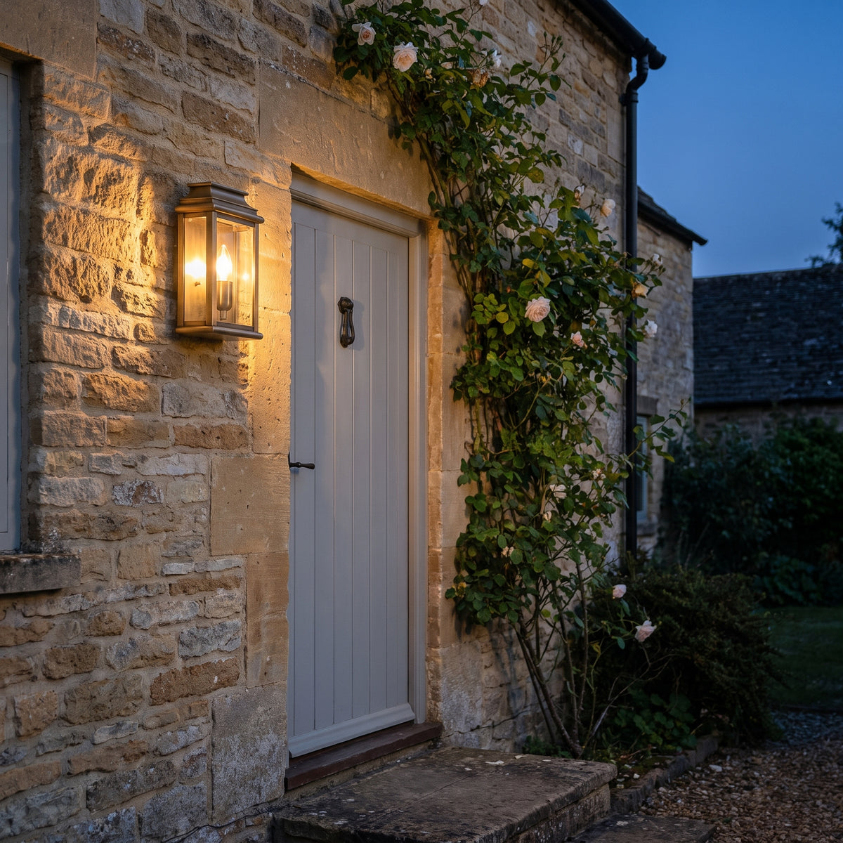 Elstead St Martins Outdoor Coastal Wall Lantern in Solid Brass, lit, in a styled room. Editorial image for the Antique Brass Outdoor Wall Lights collection.