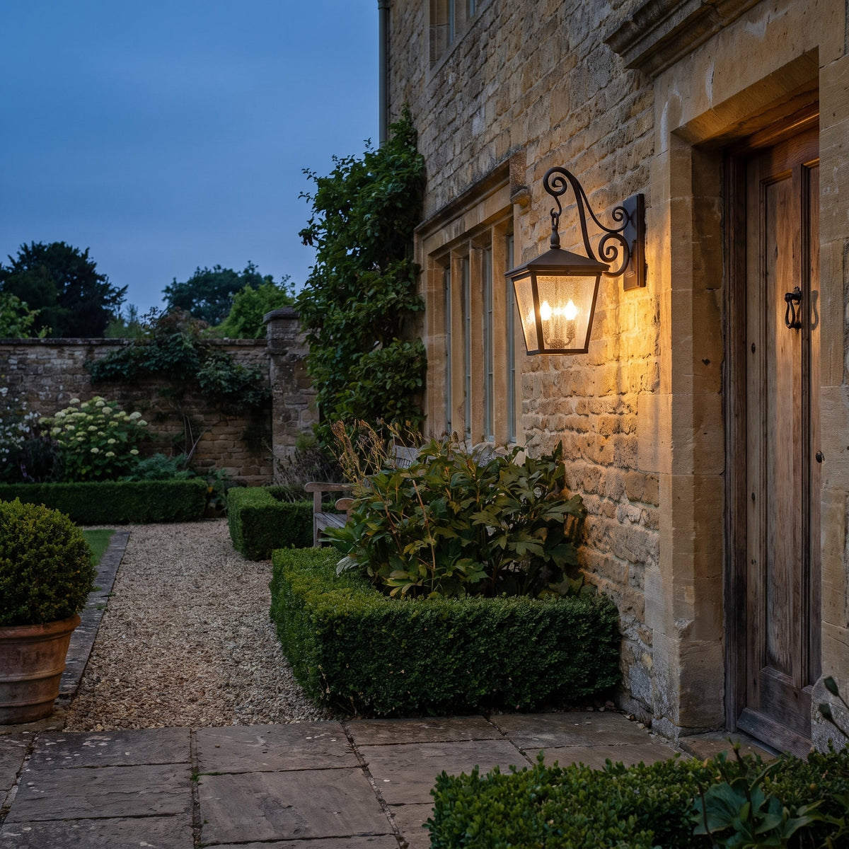 Hinkley Trellis Medium Outdoor Wall Lantern in Regency Bronze, lit, in a styled room. Editorial image for the Bronze Outdoor Lighting collection.