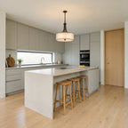 Kichler Lacey 4 Light Pendant in Mission Bronze lit over a stone kitchen island in a contemporary kitchen