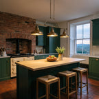 Quoizel Emery 3 Light Bar Pendant in Weathered Brass lit over a long oak-topped island in a green Victorian farmhouse kitchen