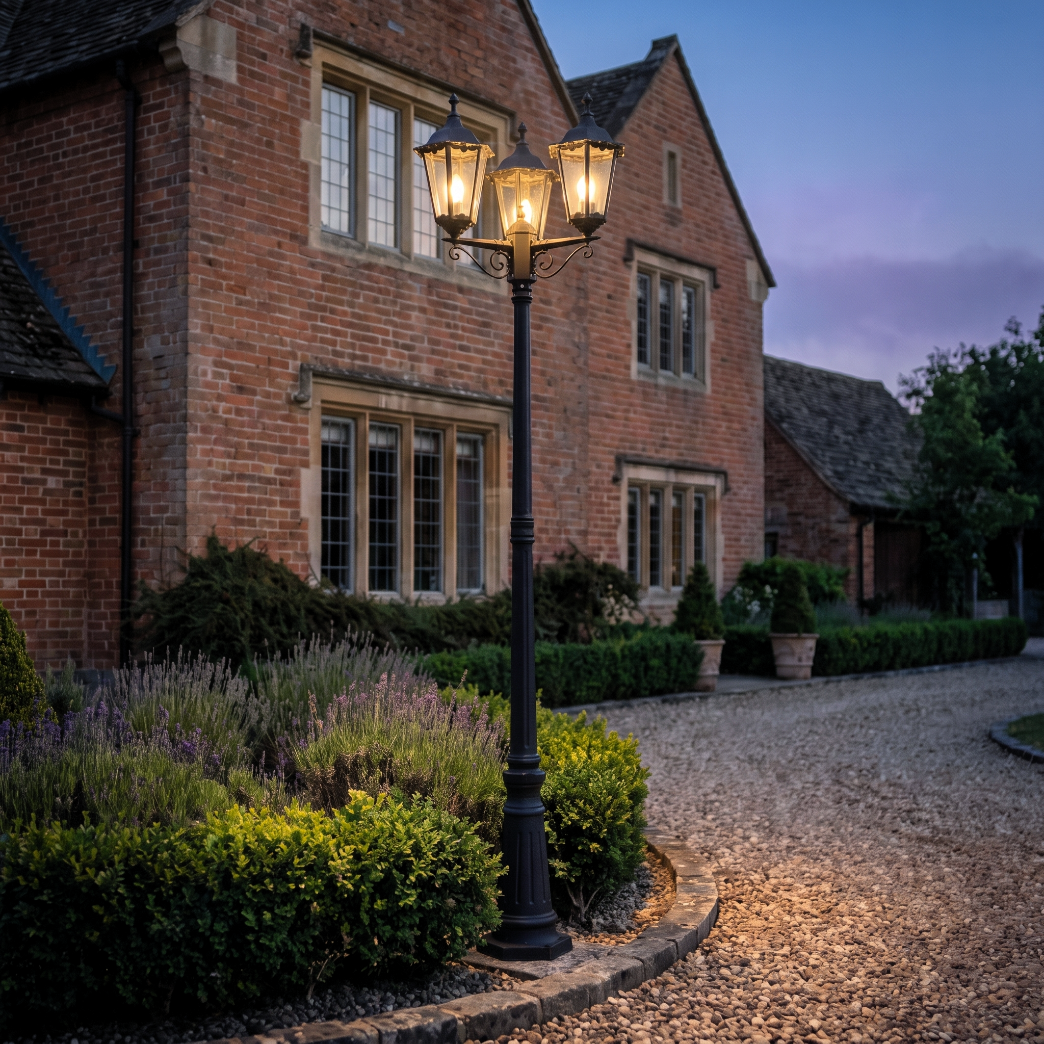 Endon Burford 3 Light outdoor lamp post in matt black, elegantly illuminating a traditional brick home and gravel driveway.